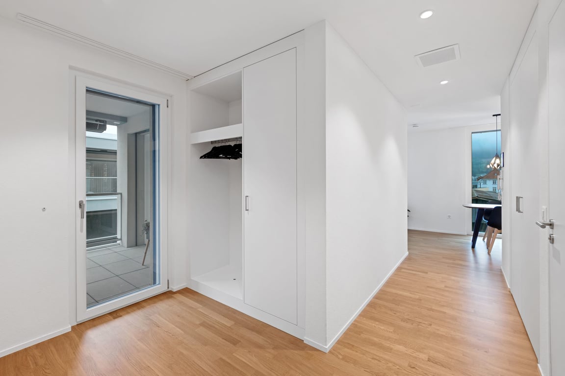 Entryway with built-in sliding wardrobe, hardwood floors, and balcony door