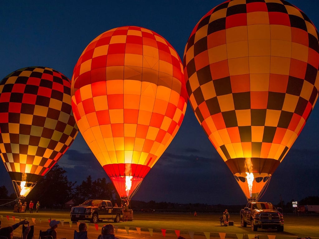 Three hot air balloons glowing together during night illumination