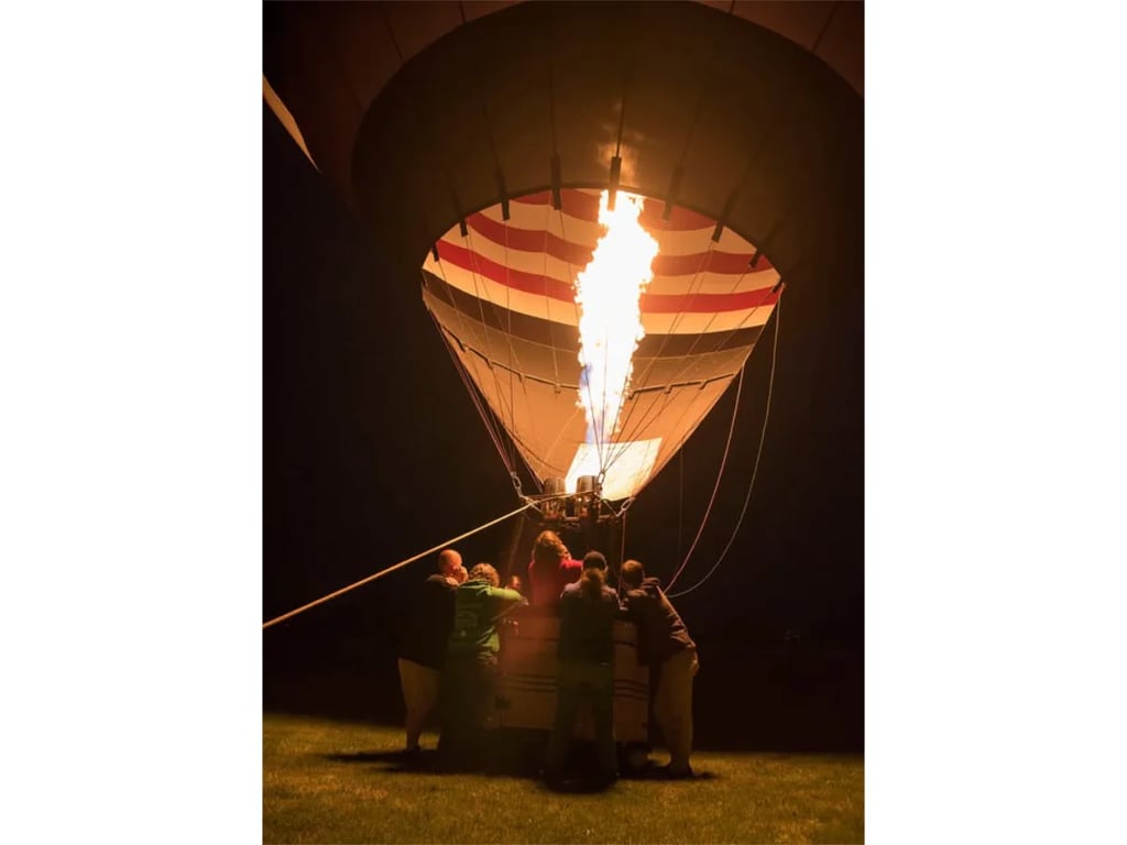 Hot air balloons lit up against the night sky