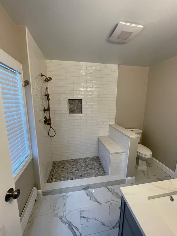 Modern bathroom with walk-in shower featuring white subway tiles, built-in bench, and mosaic tile floor