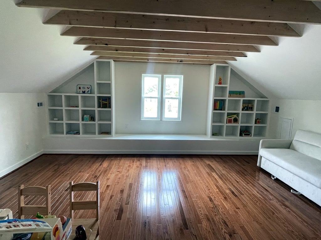 Finished attic-conversion addition with exposed wood beams, custom built-in cubby shelving, a window seat, and refinished hardwood floors