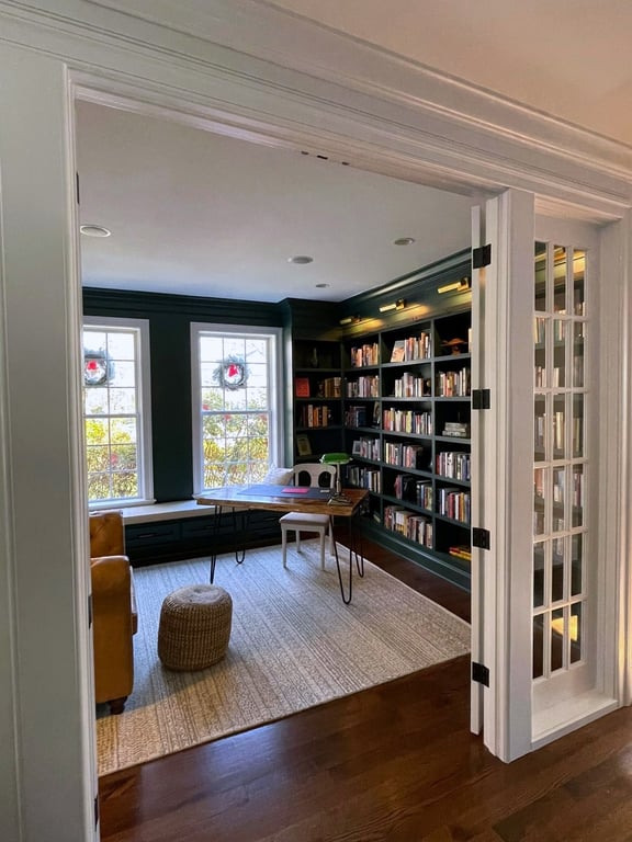 Navy home library with custom built-in shelving styled with books and a mounted TV