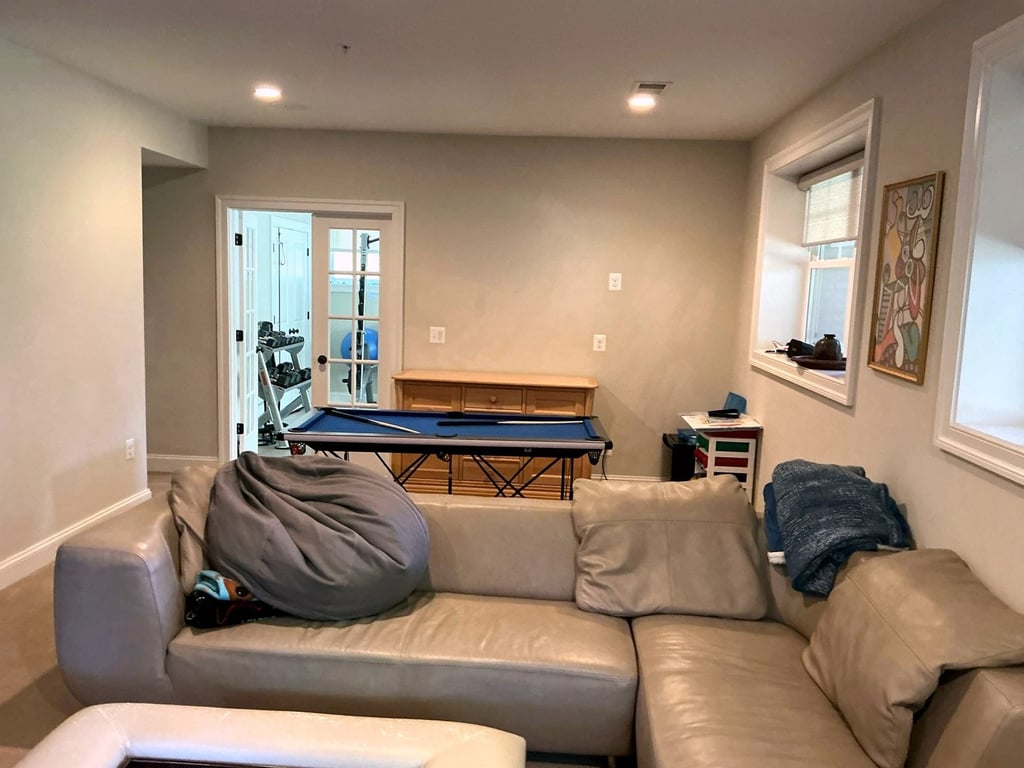 Finished basement family room with a sectional sofa, game table, and doors to the yard