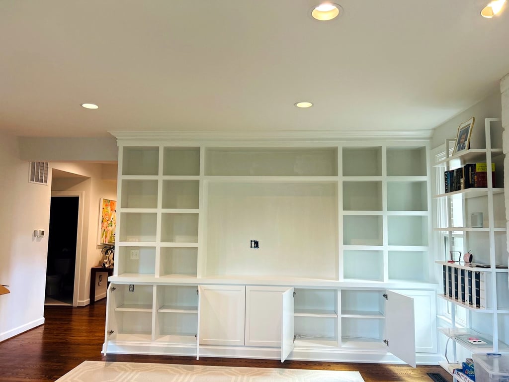 Custom white library wall of built-in shelving and cabinets spanning a full room