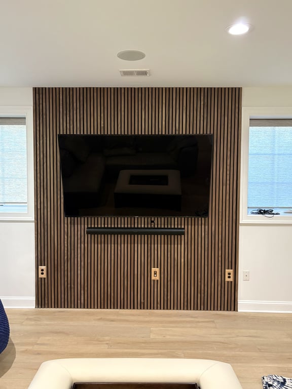 Finished basement media area with a wood-slat feature wall and mounted television