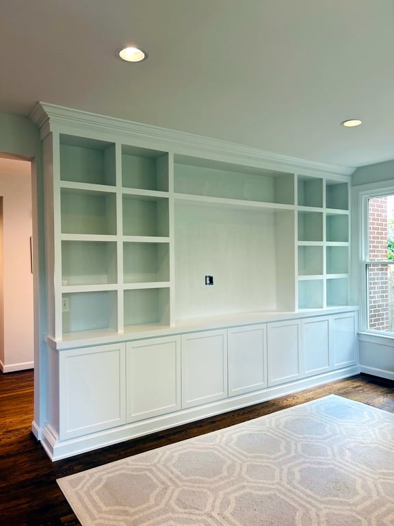 Floor-to-ceiling white built-in bookcase with base cabinets and wainscoting in a Bethesda-area home
