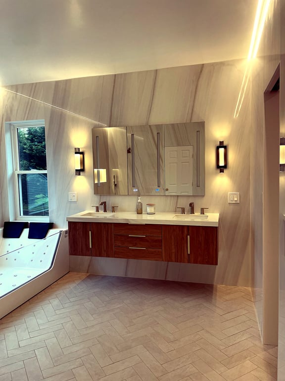 A remodeled Rockville bathroom with a floating wood vanity, backlit mirror, and large-format marble-look tile