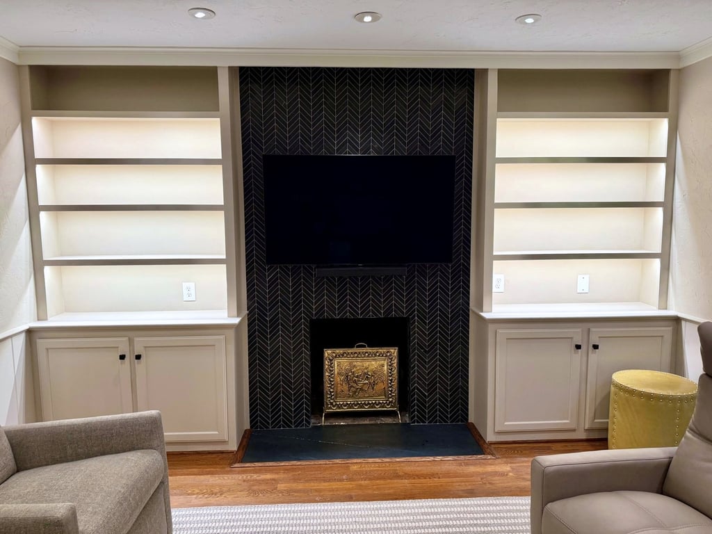 Custom white built-in bookshelves flanking a dark textured fireplace and mounted TV in a Bethesda living room by Quick Remodels