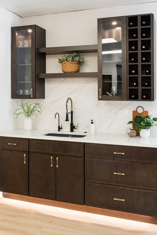 A dark-wood kitchen vignette with built-in wine storage, marble backsplash, and a gold faucet in our Bethesda showroom
