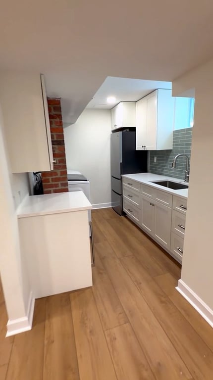 Finished basement kitchenette and laundry area with white cabinetry