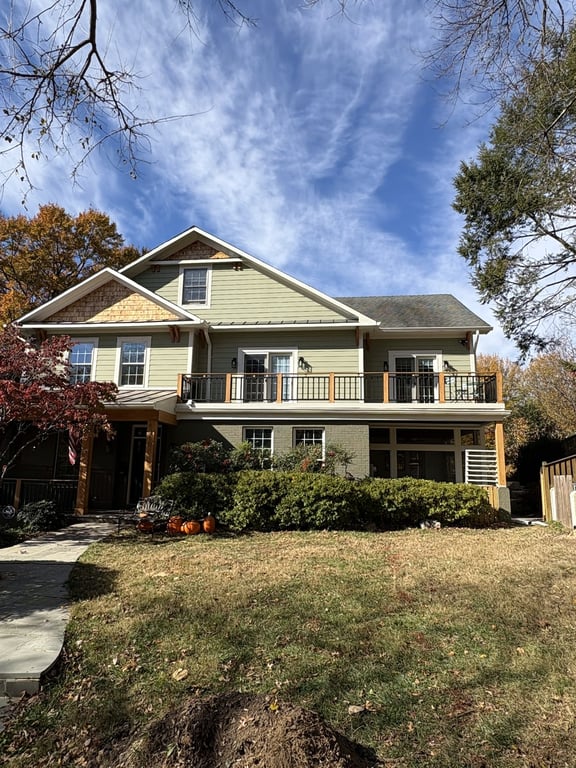 A freshly painted olive-and-tan two-tone home exterior with mature landscaping