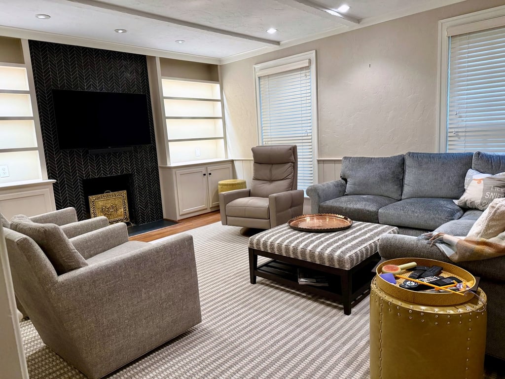 Staged living room with a custom built-in media wall, dark tile fireplace, and floating shelves by Quick Remodels