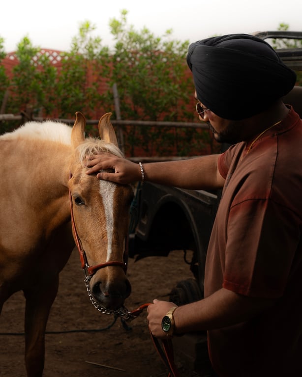 Riar Saab standing with a horse on the farm