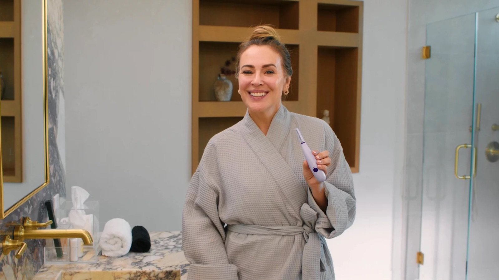 Alyssa Milano holding the SonicSmooth Pro+ device