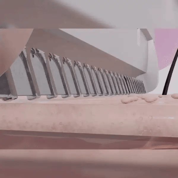 A conveyor machine slicing dough into small pieces.