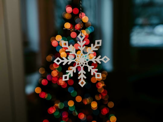 White wooden snowflake decoration lit up by multi-coloured lights