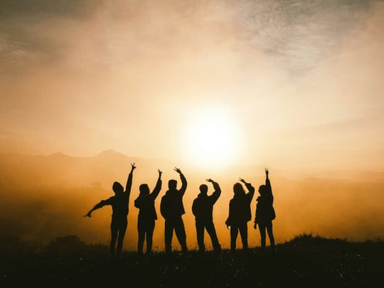 Silhouette of six people posing against a sunset