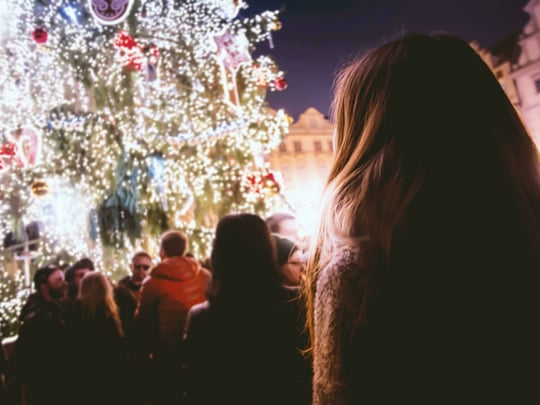 Person looking up at decorated outdoor Christmas tree