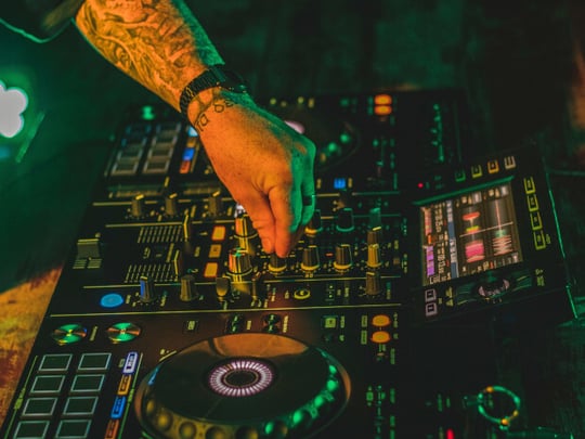 Electric mixing decks being operated by person with tattoos