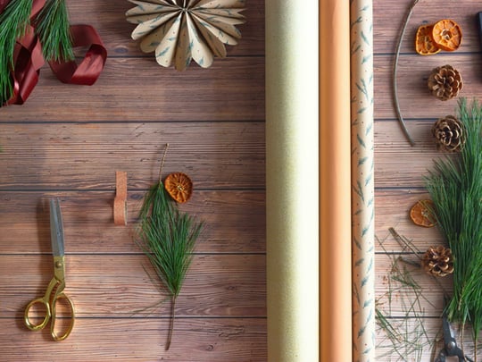 Neutral wrapping paper with Christmas tree branches and gold scissors