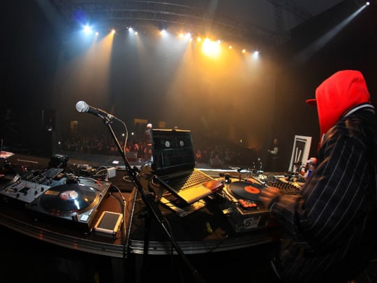 Person in a red hood DJing to a large crowd