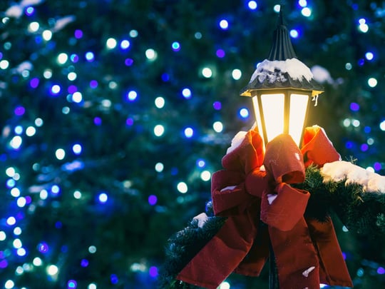 Outdoor lamp covered in snow and dressed with a red bow