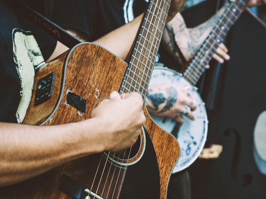 Person playing a banjo and another playing a dark wood acoustic guitar and another with a double bass
