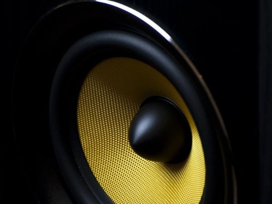 Zoomed in shot of a black speaker with bright yellow mesh