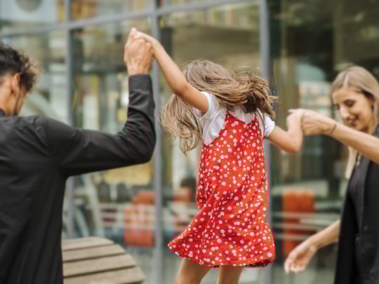 A child in a red dress with their parents