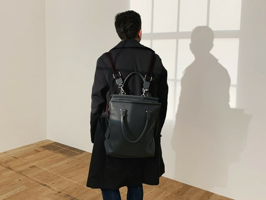 Person with black backpack and dark jacket looking at wall