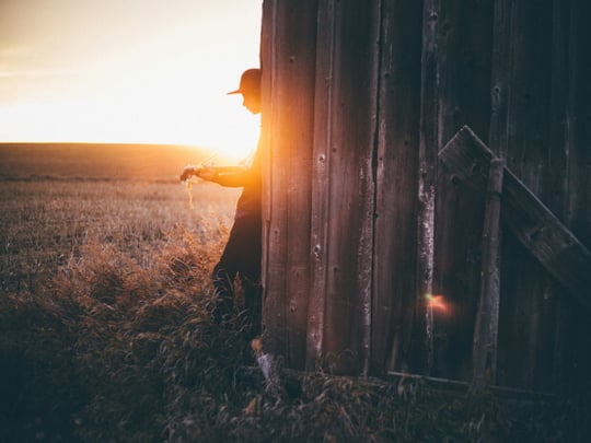 Person playing an acoustic guitar in the sunset