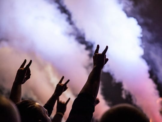 People at a concert making the sign of the horns hand gesture
