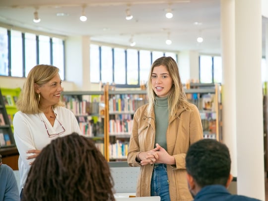 Two blonde ladies talking to a small group