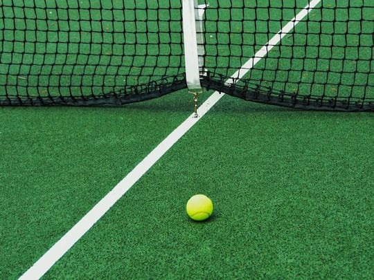 Yellow ball on green tennis court