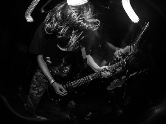 Black and white image of person with wild hair playing an electric guitar