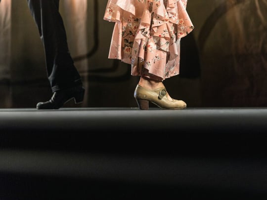 Two dancers standing back to back in the spotlight