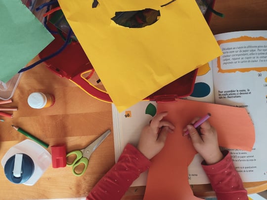A child surrounded by bright cardboard at a craft table