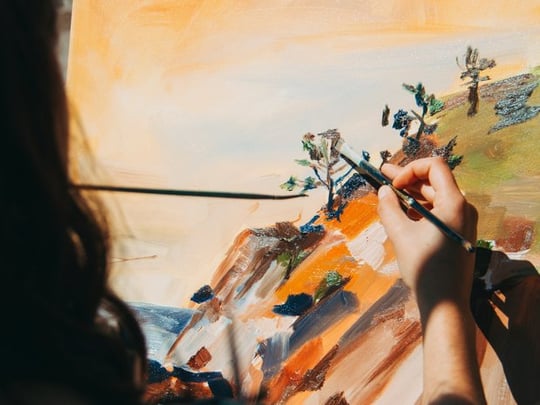 Woman painting a nature scene outside