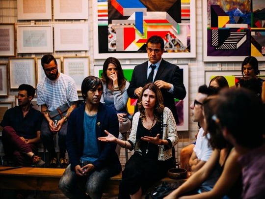 Group of people having a discussion with art on walls behind them