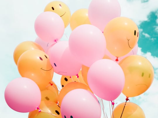 Yellow and pink balloons against a blue sky