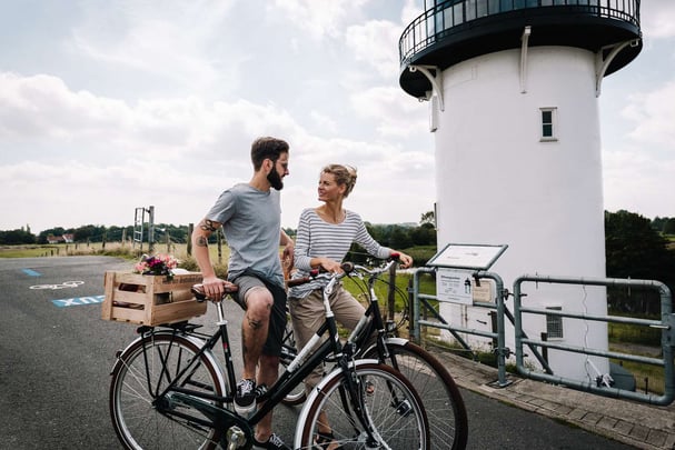Couple standing with their bicycles in front of the ‘Dicke Berta’ lighthouse
