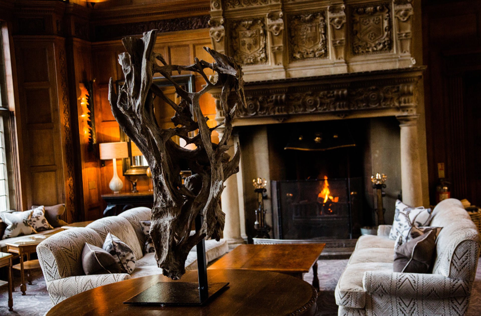 Cosy hotel lounge area with sofas and a burning log fire.