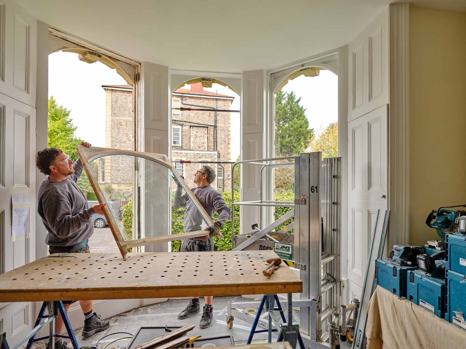 Craftsmen installing a renovated timber sash window