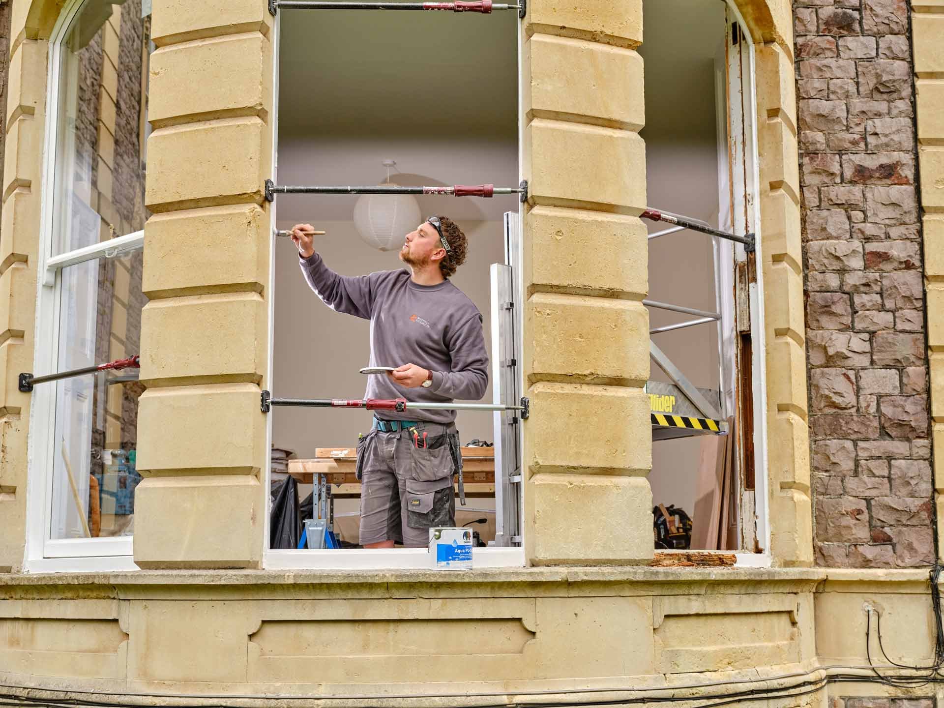 Craftsman painting the large sash window as pat of the renovation