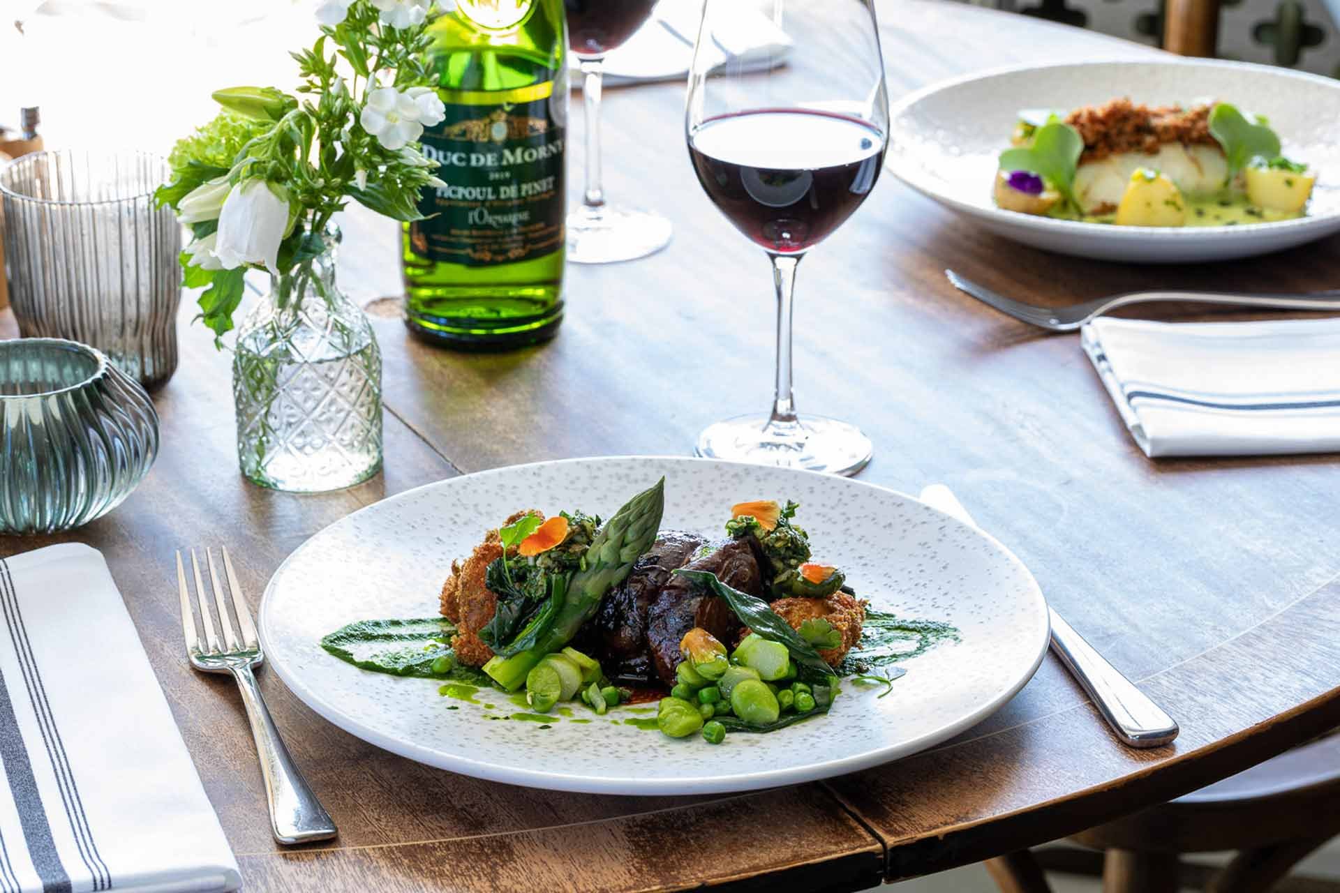 meat and asparagus dish with glass of wine