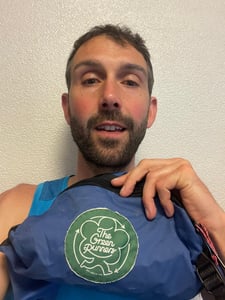 A selfie of Finlay Wild holding his The Green Runners badge, which reads "established just in time".