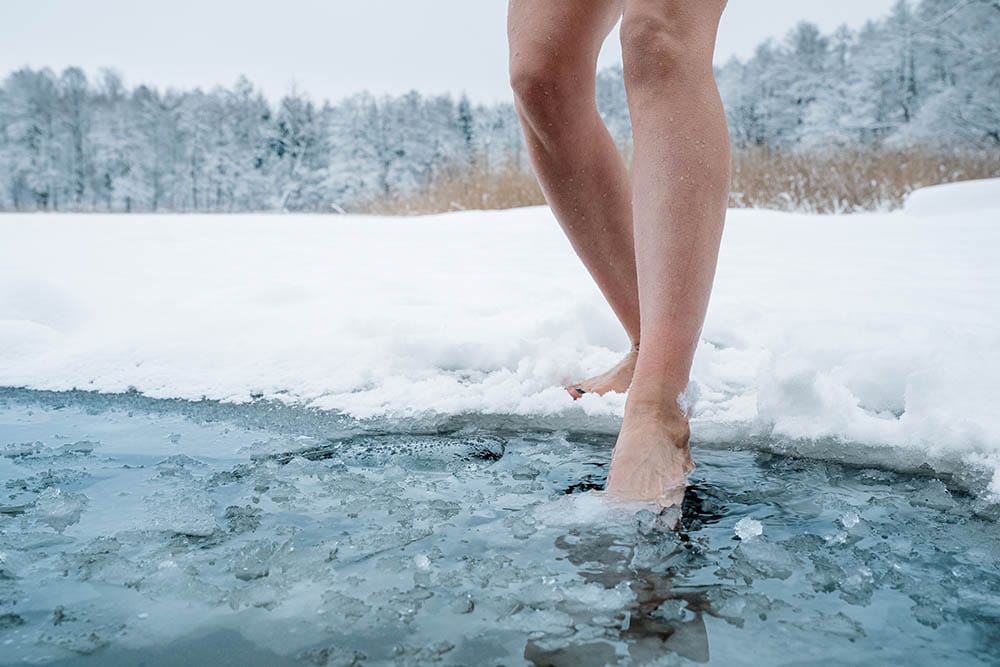 Close up of female legs getting into ice cold water