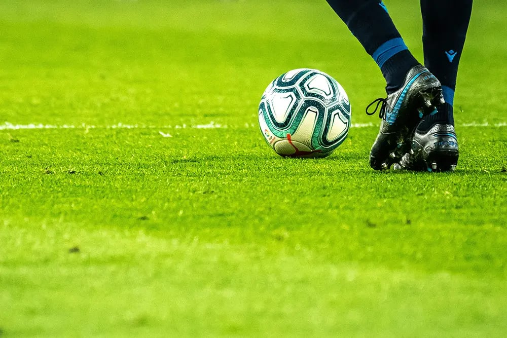 legs of a footballer wearing socks and boots dribbling a football