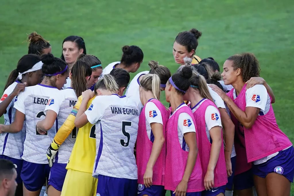 A group of women footballers in a huddle before the start of a match