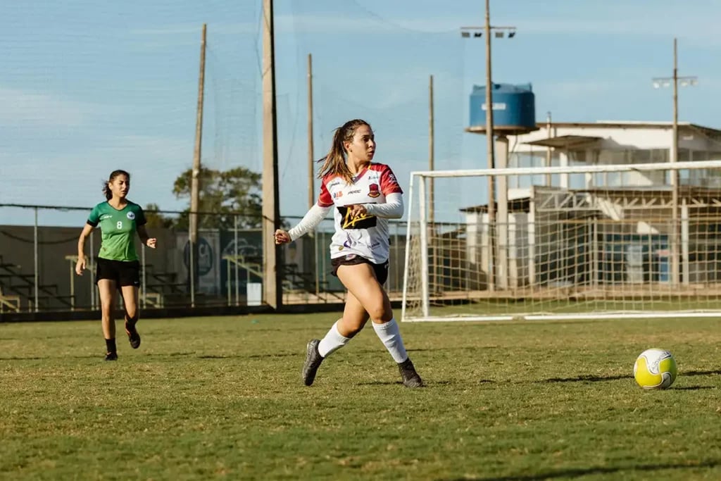 a young female footballer playing a match on a grass pitch
